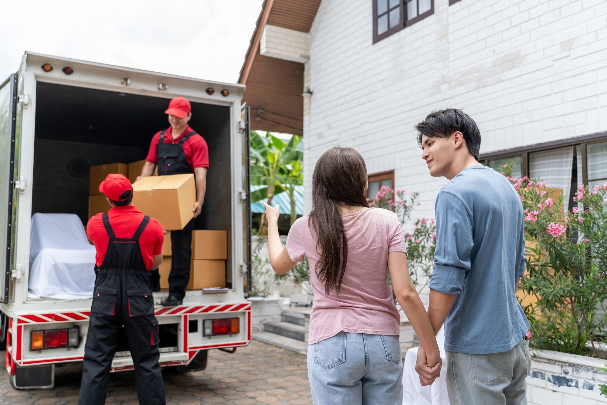 Asian young couple look at truck car while moving to new house together.